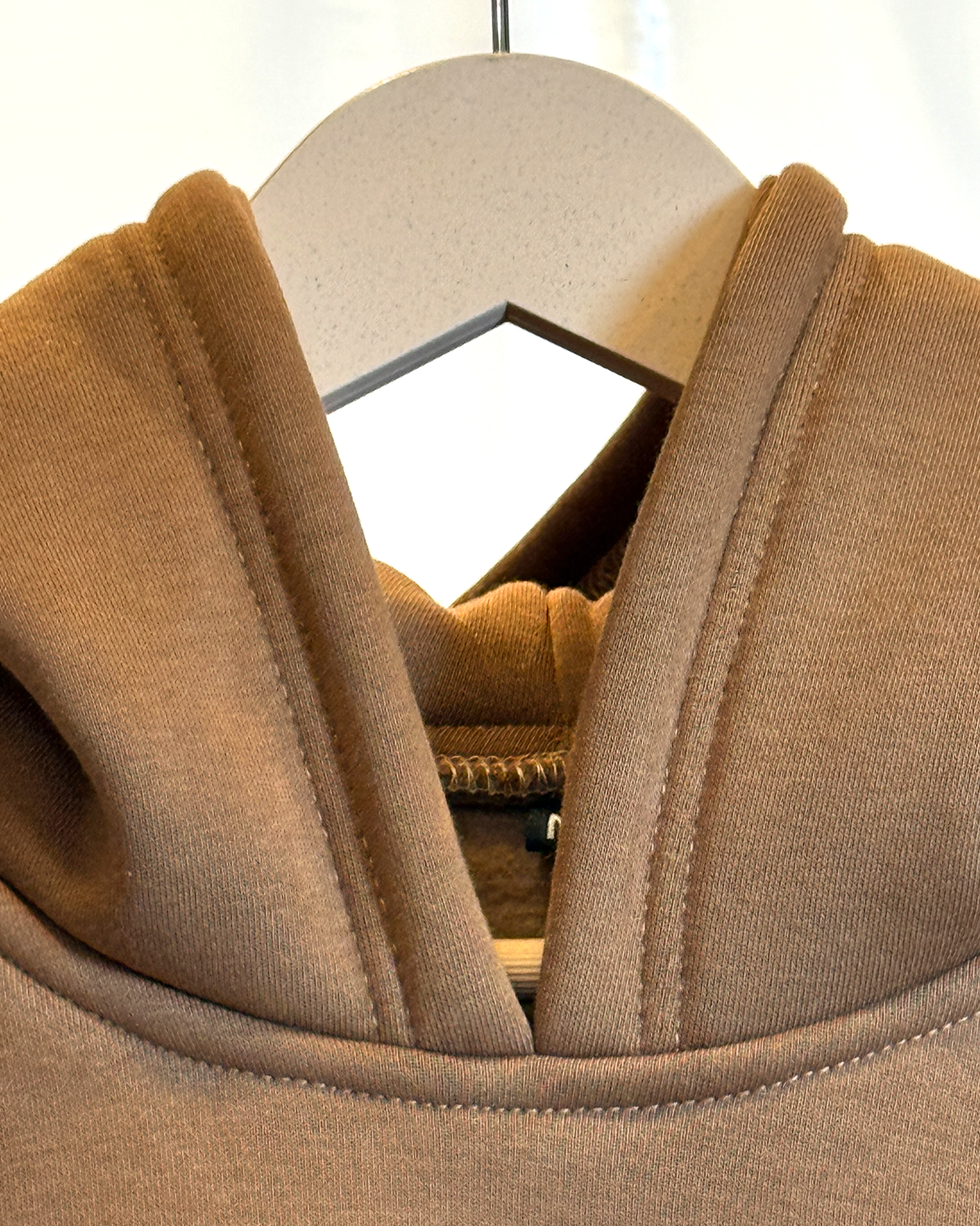 Zor Lifestyle, Brown Hoodie, Hoodies for men, Hoodies for Women, Close-up of a brown hoodie hood on a hanger with a blurred background