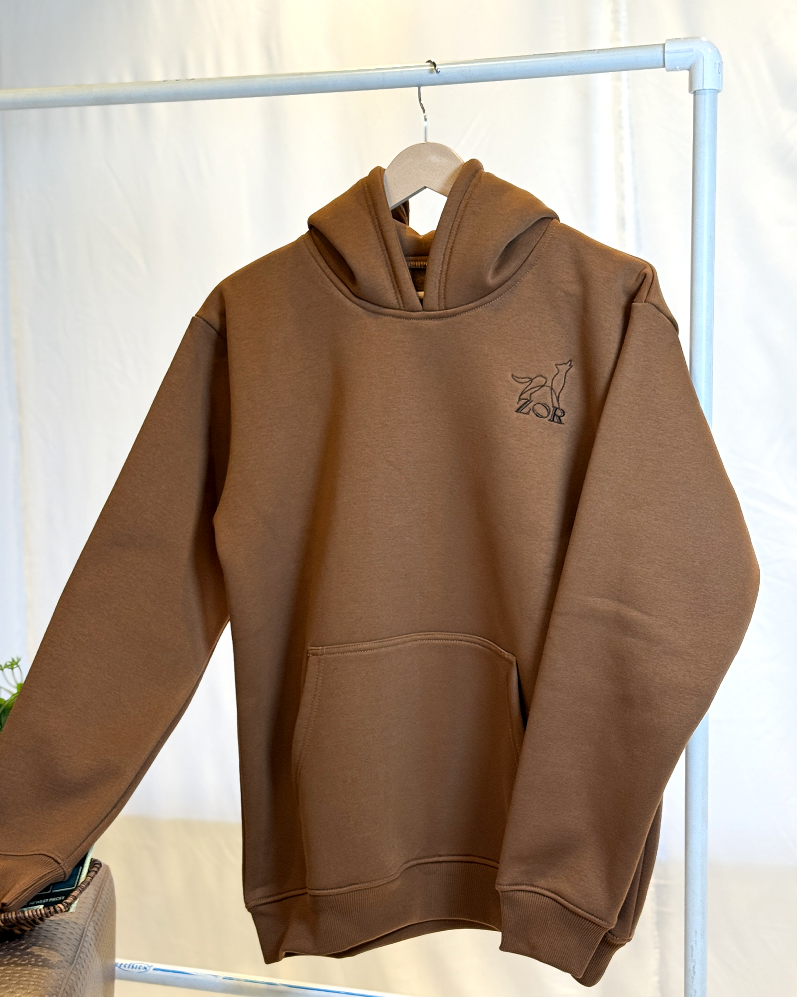 Zor Lifestyle, Brown Hoodie, Hoodies for men, Hoodies for Women, Brown hoodie with a logo on a hanger against a white background